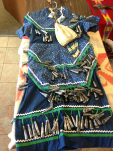 The jingle dress has many metal cones attached to it, making it quite a heavy piece of clothing. It is used in prayer and ritualistic dances and makes a characteristic sound as the wearer moves. 