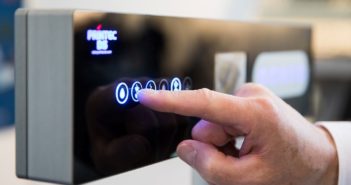 A hand touching a automated coffee maker touchscreen