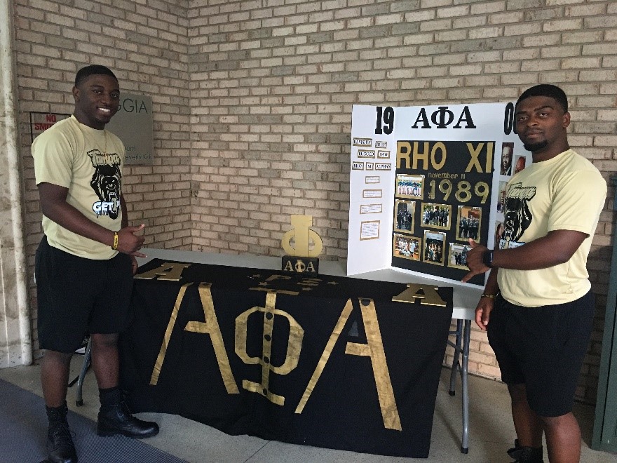 Alpha Phi Alpha members with their table.