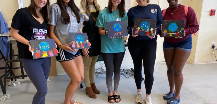 Group of students and their paintings in a group picture.
