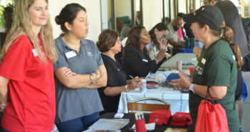 Multiple people standing next to tabling booth.