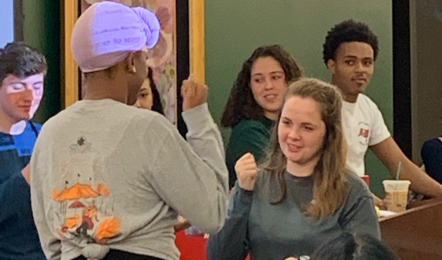 Two students in the front of the SCC Boardrooms competing at a change for one of the Bingo prizes by playing Rock, paper, scissors.