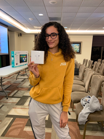 Student winner from bingo with the AirPods prize in right hand.