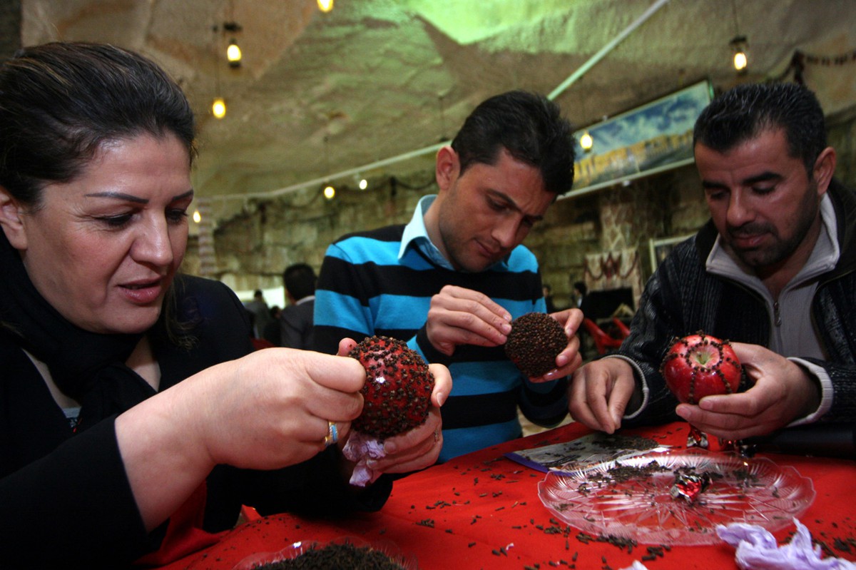 People making decorative covered apples on red table.