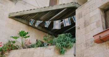 Old stone building with plants and hanging Israel flags