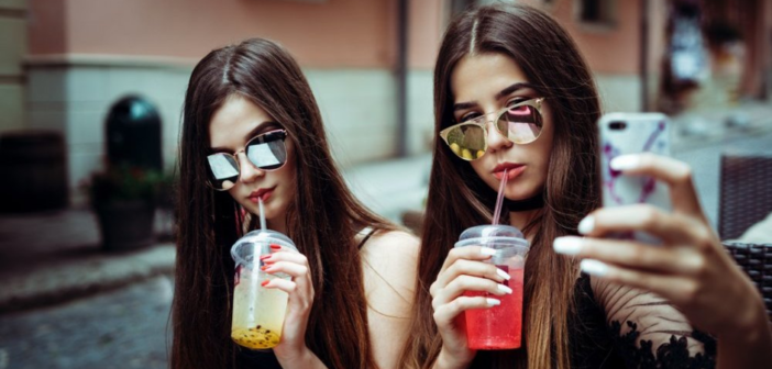 Two women with glasses and drinks taking a selfie.