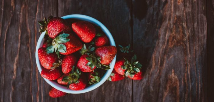 A white bowl with strawberries inside