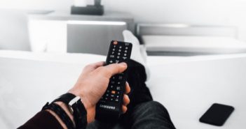 A hand holding a tv remote pointing to the screen.