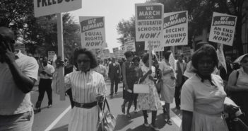 A peaceful civil rights march in the street, women holding signs
