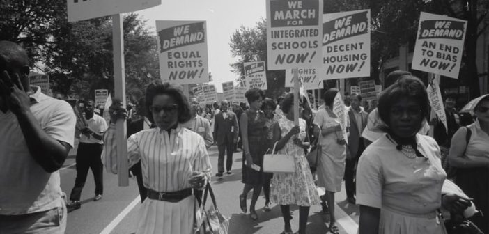 A peaceful civil rights march in the street, women holding signs