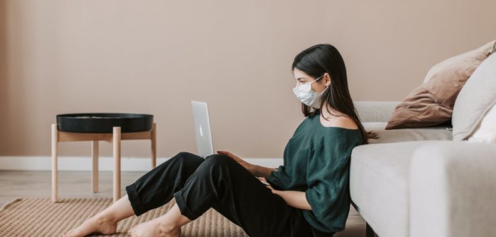 A girl looking at her computer while wearing a mask