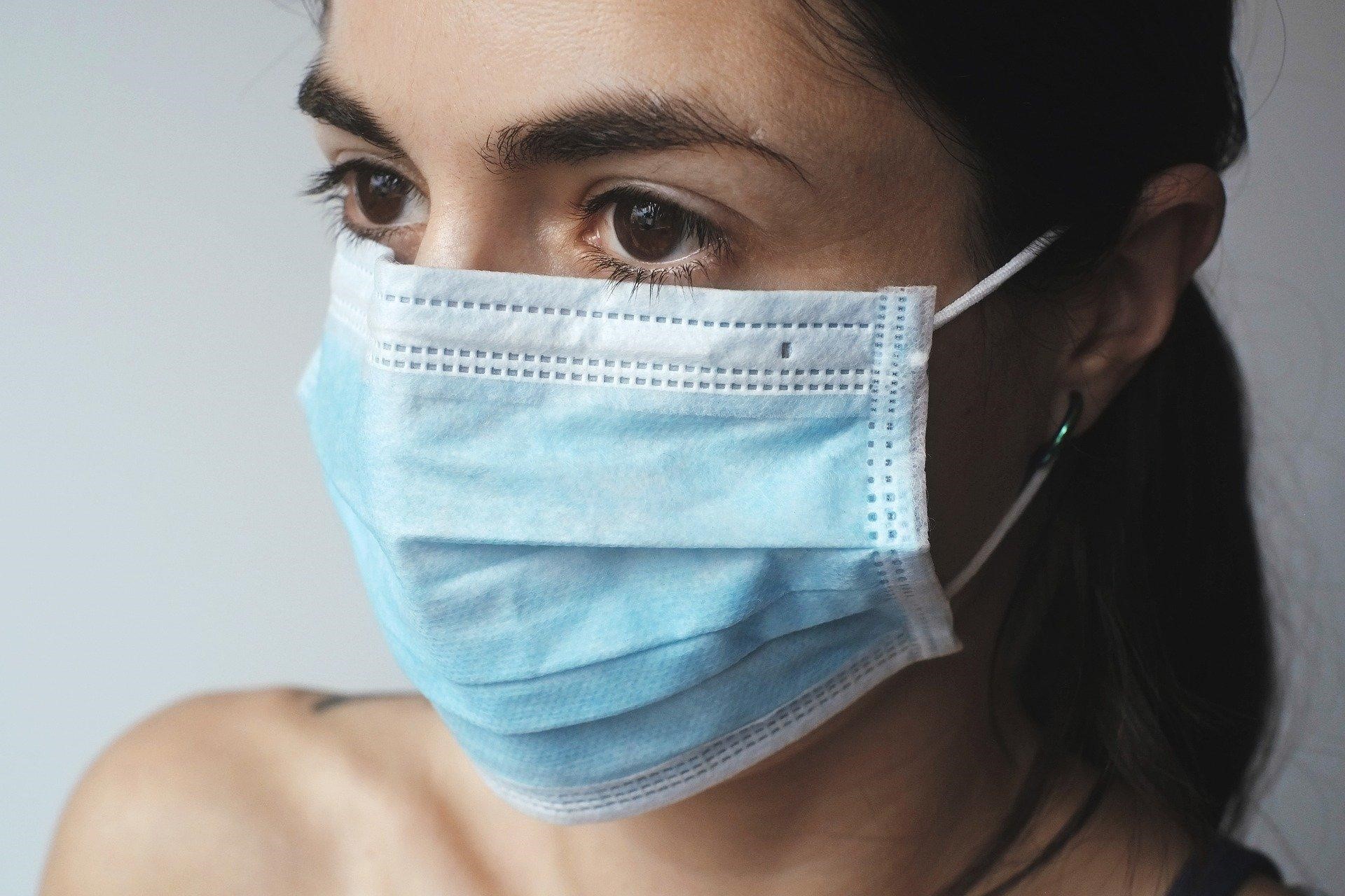 A lady wearing a blue and white disposable mask