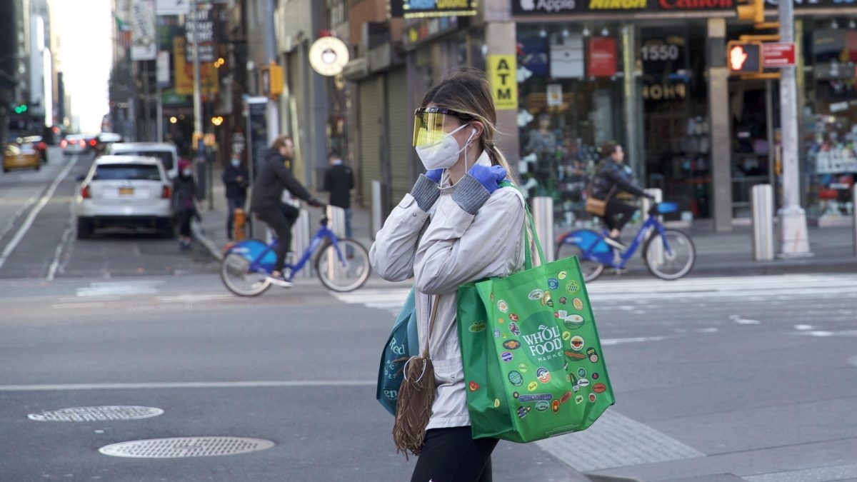 A woman carrying bags walking with a white mask