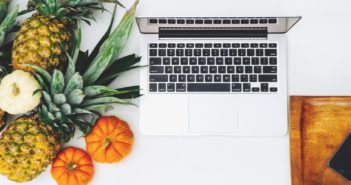 A computer next to some fruit