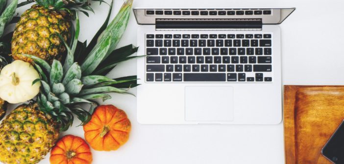 A computer next to some fruit