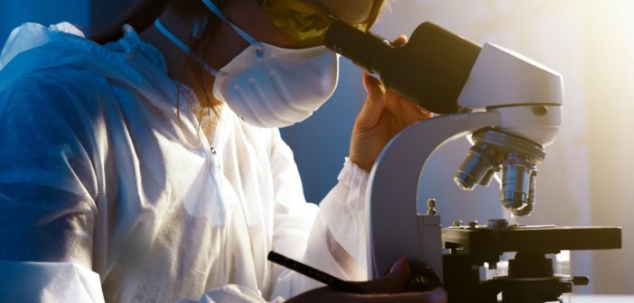 A woman in a lab coat looking at a microscope