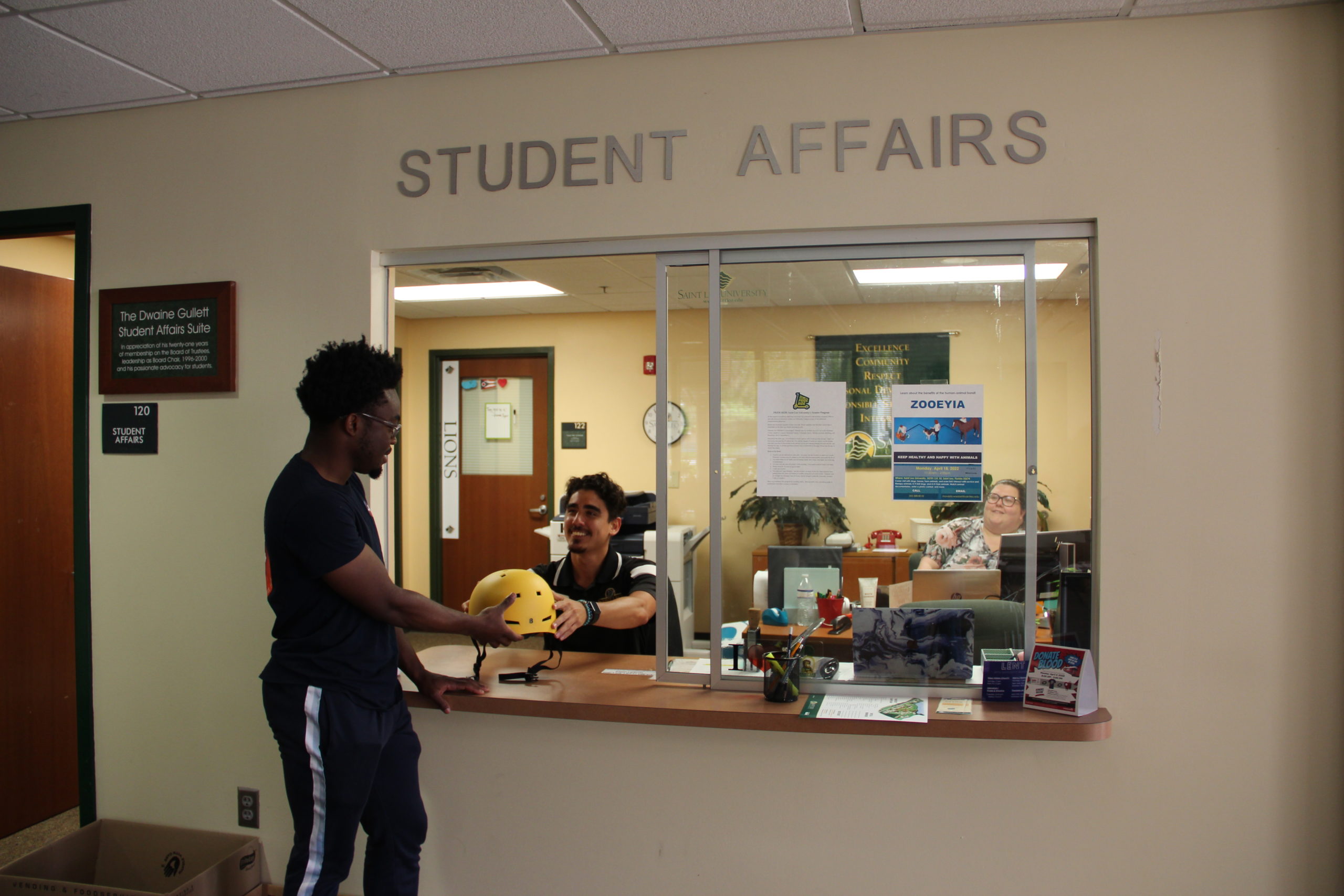 A boy receiving a helmet from Student Affairs